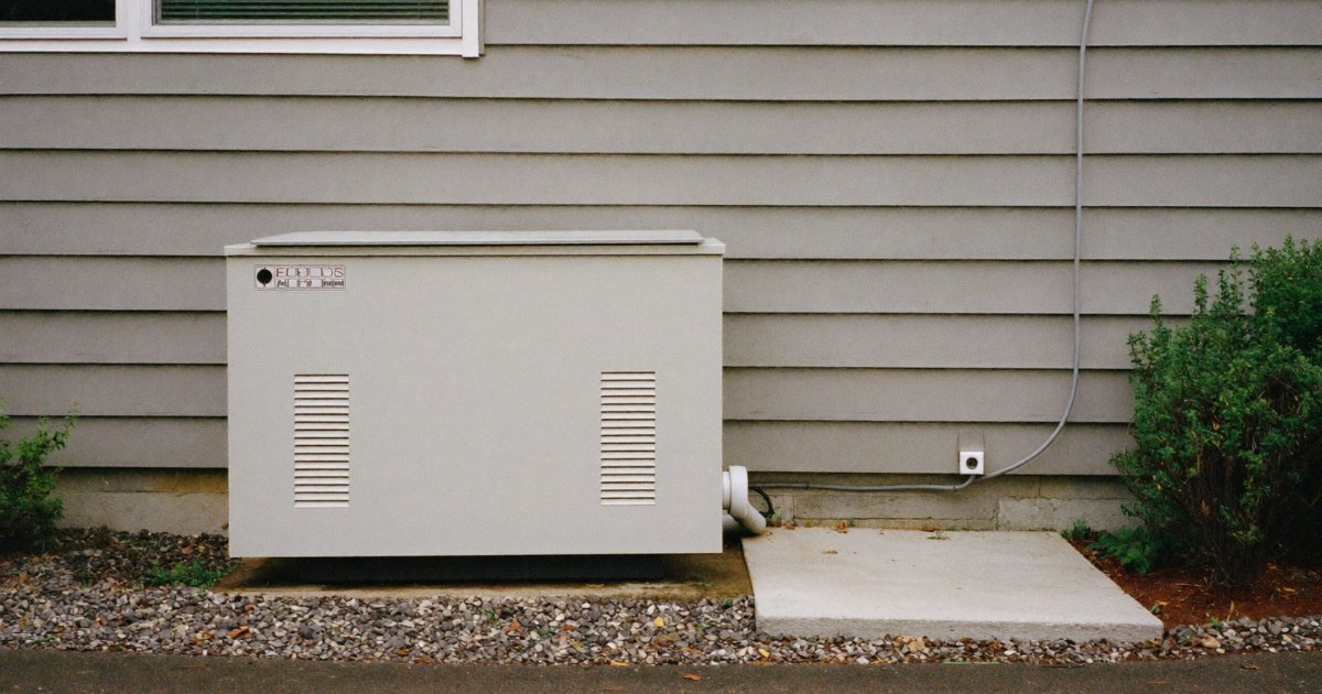 Compact standby generator on a pad beside a single-story house