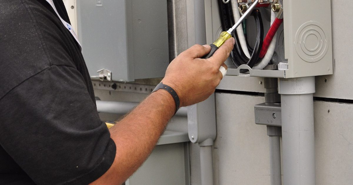 Electrician installing an electrical meter base on a house