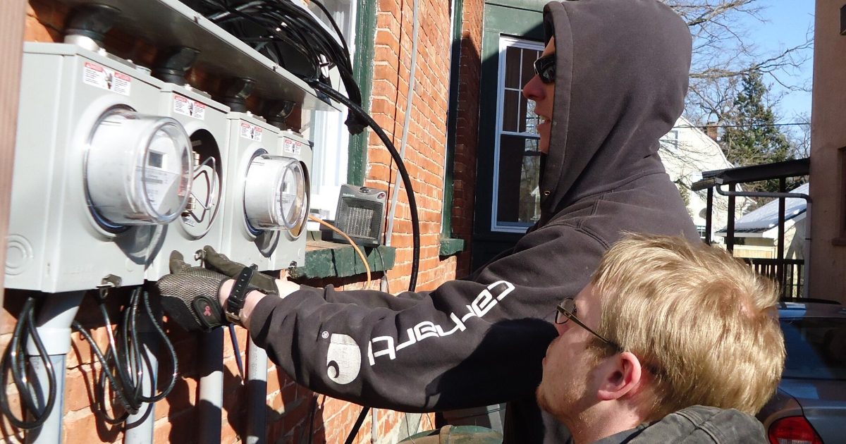 Electricians installing electrical panels on a house