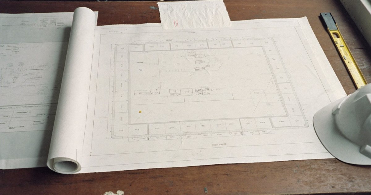 Site plan, permit forms, hard hat and tape measure on a table