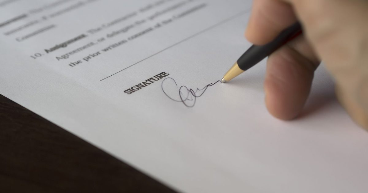Hand signing a contract with a pen