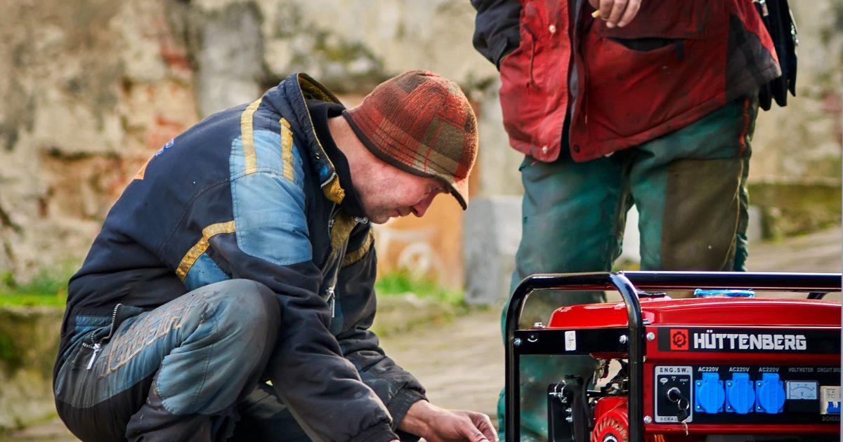 Two technicians servicing a generator outdoors